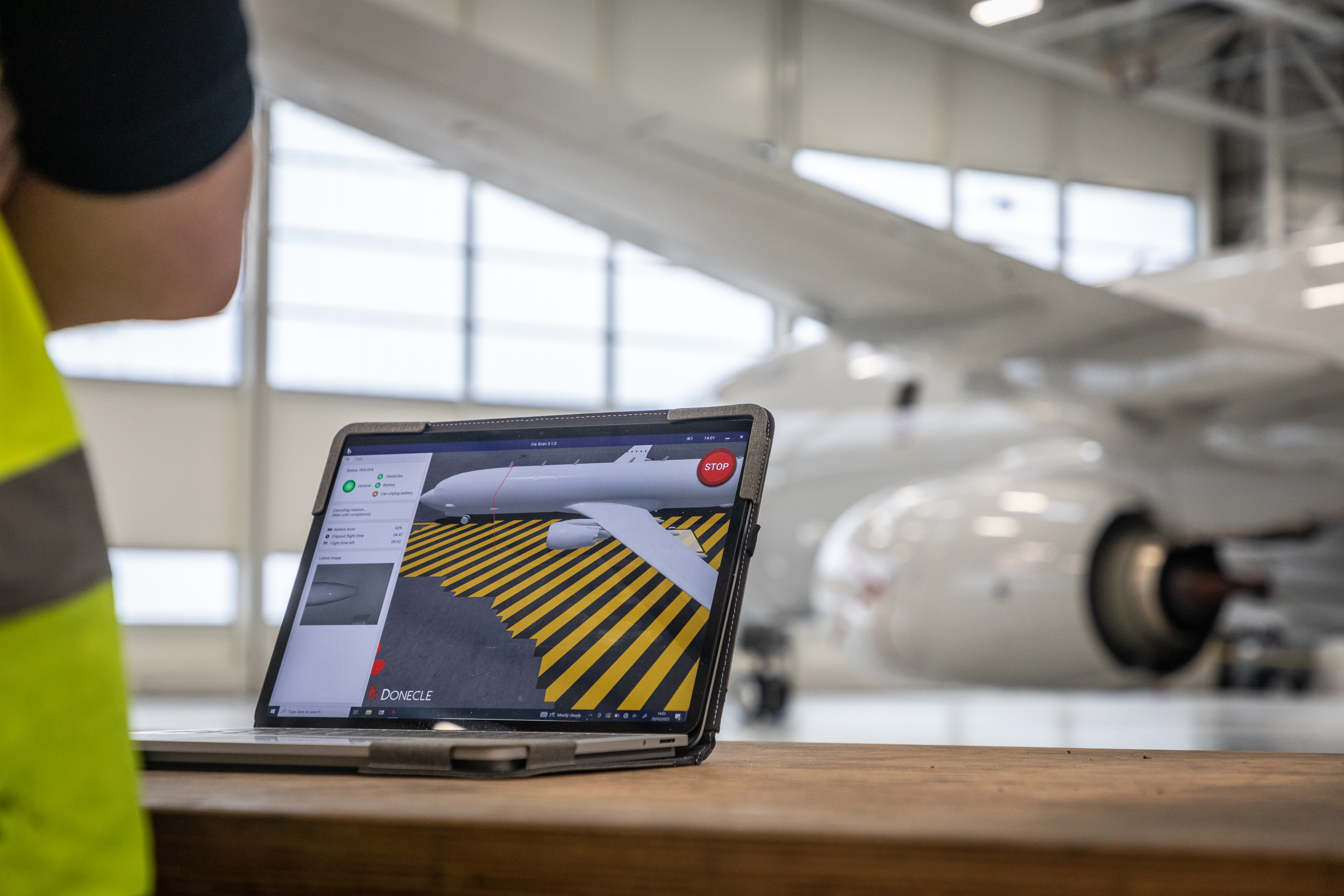 Engineers look at a laptop showing a display of the aircraft while the drone flies alongside it